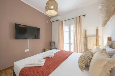 a bedroom with a bed with a flat screen tv on the wall at Boho Pennie Home by CloudKeys in Athens
