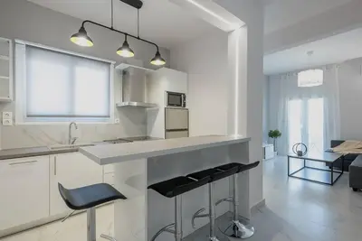 a kitchen with white cabinets and a counter with stools at Patisia metro Station 100m in Athens
