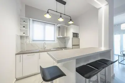 a kitchen with white cabinets and a counter and stools at Patisia metro Station 100m in Athens