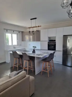 a kitchen with a table and chairs and a couch at New minimal apartment,10' from Athens airport in Spáta