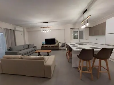 a living room and kitchen with a couch and a table at New minimal apartment,10' from Athens airport in Spáta