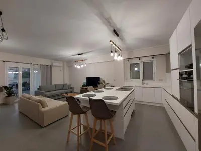 a kitchen and living room with a table and chairs at New minimal apartment,10' from Athens airport in Spáta
