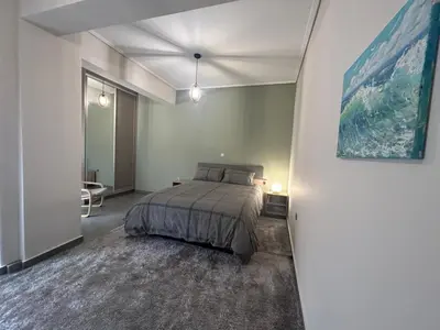a bedroom with a bed and a painting on the wall at New minimal apartment,10' from Athens airport in Spáta
