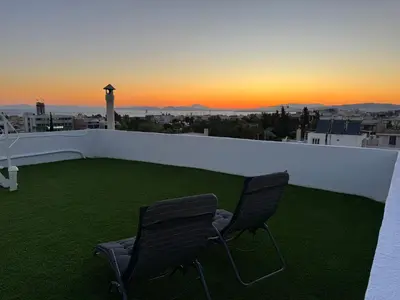 two chairs sitting on a balcony with the sunset at Skyline oasis rooftop in Athens