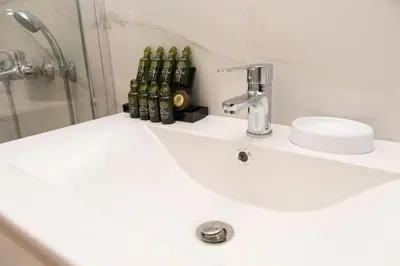 a bathroom with a sink with bottles on it at Renovated spacious flat 7min to subway station-(ΝIK_A) in Athens