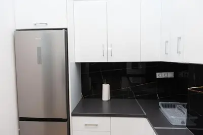 a stainless steel refrigerator in a kitchen with white cabinets at Renovated spacious flat 7min to subway station-(ΝIK_A) in Athens