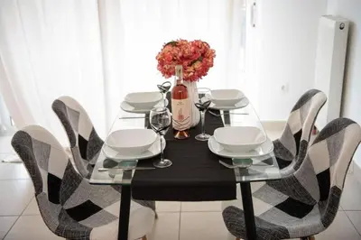 a dining room table with chairs and a bottle of wine at Overlooking park flat close to the Piraeus Port-(DRAP-A7) in Piraeus