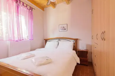 a bedroom with a bed with white sheets and a window at Sea Breeze Garden Maisonette - Porto Rafti by ΜΡS in Porto Rafti