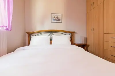 a bedroom with a white bed with a wooden headboard at Sea Breeze Garden Maisonette - Porto Rafti by ΜΡS in Porto Rafti