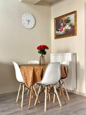 a dining room table with white chairs and a clock at Dafni City Apartment 1 in Athens