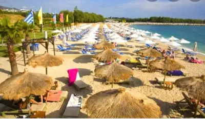 a beach with many straw umbrellas and the ocean at EcoStay-Scandy,2bdr cozy apartment by the sea in Alimos in Athens
