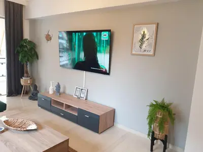 a living room with a tv on a wall at EcoStay-Scandy,2bdr cozy apartment by the sea in Alimos in Athens