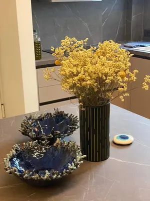 a vase with yellow flowers and two plates on a table at Sapfo Luxury Apartment 1 in Athens in Athens