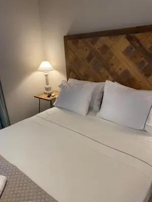 a bedroom with a white bed with a wooden headboard at Aelia Houses2 in Agia Marina Aegina