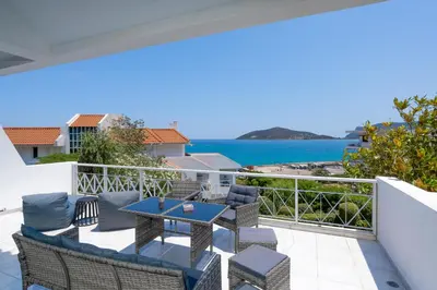 a balcony with a table and chairs and the ocean at Phos Apartment by A&D Properties in Porto Rafti
