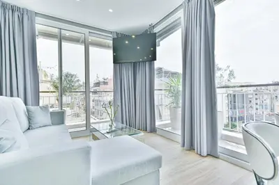 a living room with a white couch and large windows at Glassy Apartment in Athens