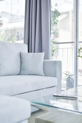 a living room with a white couch and a glass table at Glassy Apartment in Athens