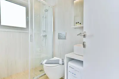a white bathroom with a shower and a toilet at Glassy Apartment in Athens