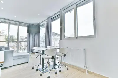a living room with a table and chairs and windows at Glassy Apartment in Athens