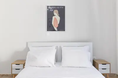 a bedroom with a bed with white sheets and a poster at Sweet & New Studio-Center Athens in Athens