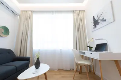 a living room with a couch and a desk with a laptop at Minimal apartment in Plaka in Athens
