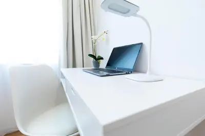 a laptop computer sitting on a white desk with a lamp at Minimal apartment in Plaka in Athens