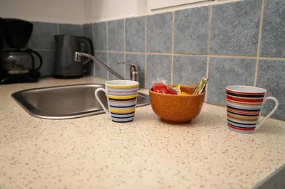 three cups on a kitchen counter with a bowl of fruit at Platinum Central Apartment in Athens