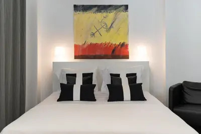 a bedroom with a white bed with black and white pillows at Executive Apartment in Kolonaki in Athens