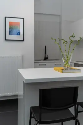 a white kitchen with a table with a vase on it at Executive Apartment in Kolonaki in Athens