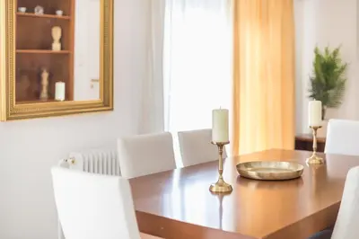 a dining room table with white chairs and a mirror at Athens Del Sol Suite in Athens