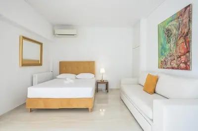 a white bedroom with a bed and a couch at Athens Del Sol Suite in Athens