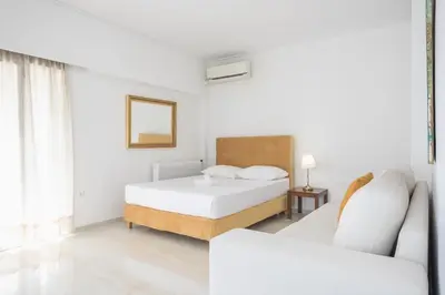 a white bedroom with a bed and a couch at Athens Del Sol Suite in Athens