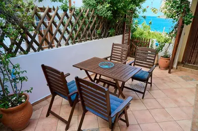 a patio with a wooden table and chairs at The Captain's Penthouse in Porto Rafti