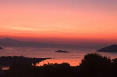 a sunset over the ocean with islands in the distance at The Captain's Penthouse in Porto Rafti