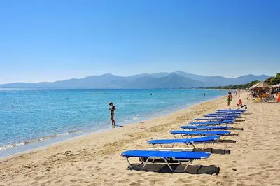a row of blue beach loungers on a beach at The Captain's Penthouse in Porto Rafti