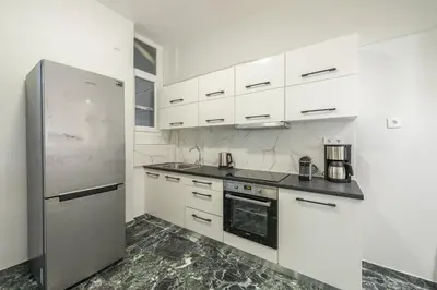 a kitchen with white cabinets and a stainless steel refrigerator at Victoria Divas Paradise Suite in Athens