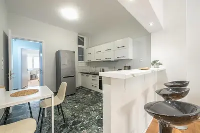 a kitchen with white cabinets and a table and chairs at Victoria Divas Paradise Suite in Athens