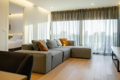 a living room with a couch and a large window at Earth Boutique Apartments next to Stavros Niarchos in Athens