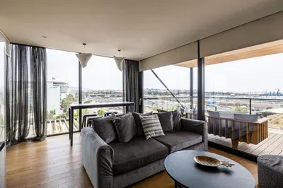 a living room with a couch and large windows at Earth Boutique Apartments next to Stavros Niarchos in Athens