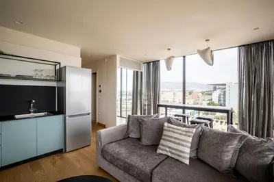 a living room with a couch and a large window at Earth Boutique Apartments next to Stavros Niarchos in Athens
