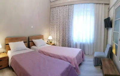 a hotel room with two beds and a window at The Traditional Athenian house for 6, near metro in Athens
