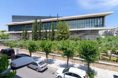 a building with cars parked in a parking lot at Spacious 2 Bedroom Apartment In Koukaki in Athens