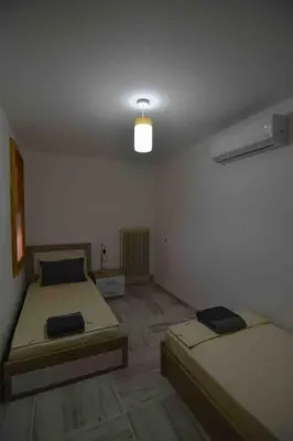 a room with two beds and a light on the ceiling at Agia Marina apartment in Aghia Marina