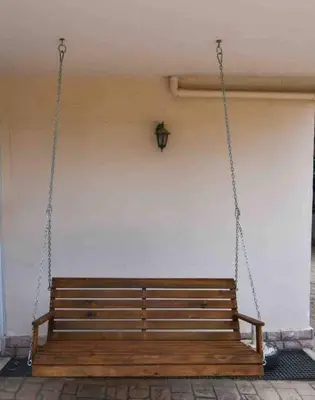 a wooden bench chained to a wall at Agia Marina apartment in Aghia Marina