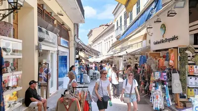 a group of people walking through a street with shops at Cozy apartment in Plaka in Athens