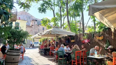 a group of people sitting at tables with an umbrella at Cozy apartment in Plaka in Athens