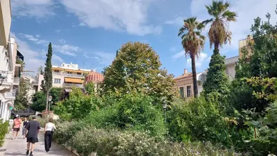 people walking down a sidewalk in a city with palm trees at Cozy apartment in Plaka in Athens