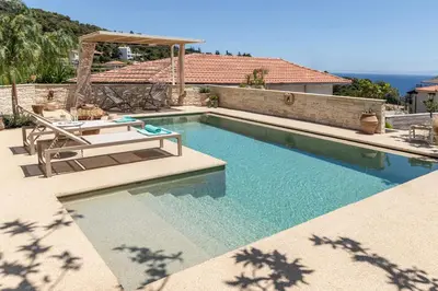 a swimming pool with two chairs and a table at Casa Meraki by A&D Properties in Porto Rafti