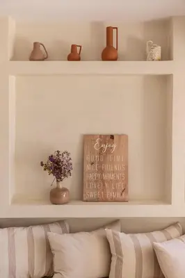 a shelf above a couch with a vase of flowers at Casa Meraki by A&D Properties in Porto Rafti