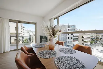 a dining room with a table and chairs and a large window at Costa Alimos by Verde Apartments in Athens